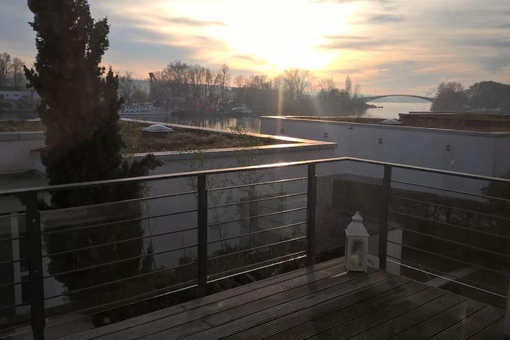 einen Balkon mit Blick auf den Fluss und den Sonnenuntergang in der Unterkunft Wohnen am Wasser in Wiesbaden