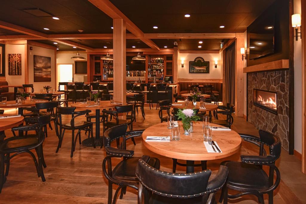a restaurant with wooden tables and chairs and a fireplace at Harbour House Hotel in Ganges