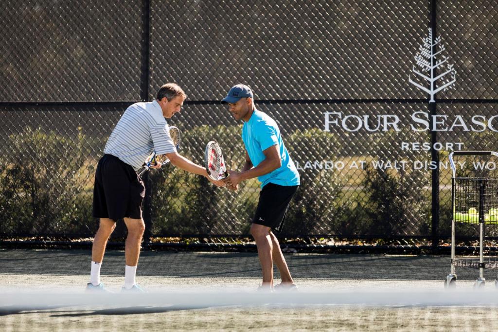 two men shaking hands on a tennis court at Four Seasons Resort Orlando at Walt Disney World Resort in Orlando