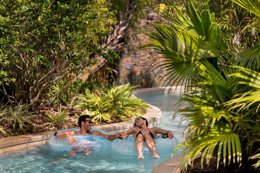 two men are sitting in the pool at a resort at Four Seasons Resort Orlando at Walt Disney World Resort in Orlando
