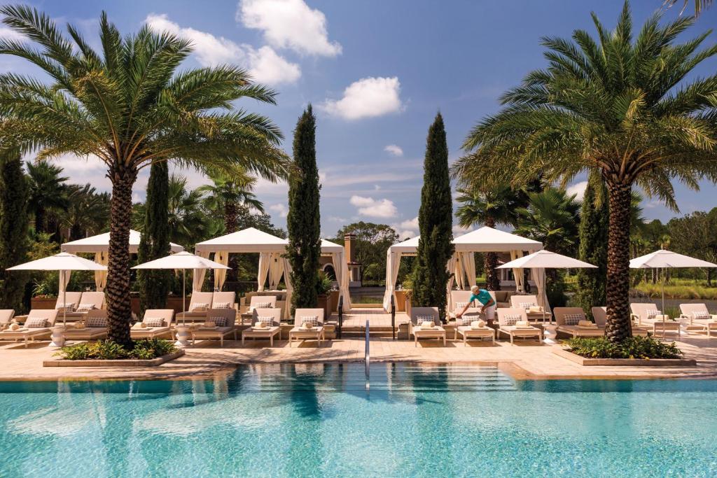 a pool with chaise lounge chairs and palm trees at Four Seasons Resort Orlando at Walt Disney World Resort in Orlando