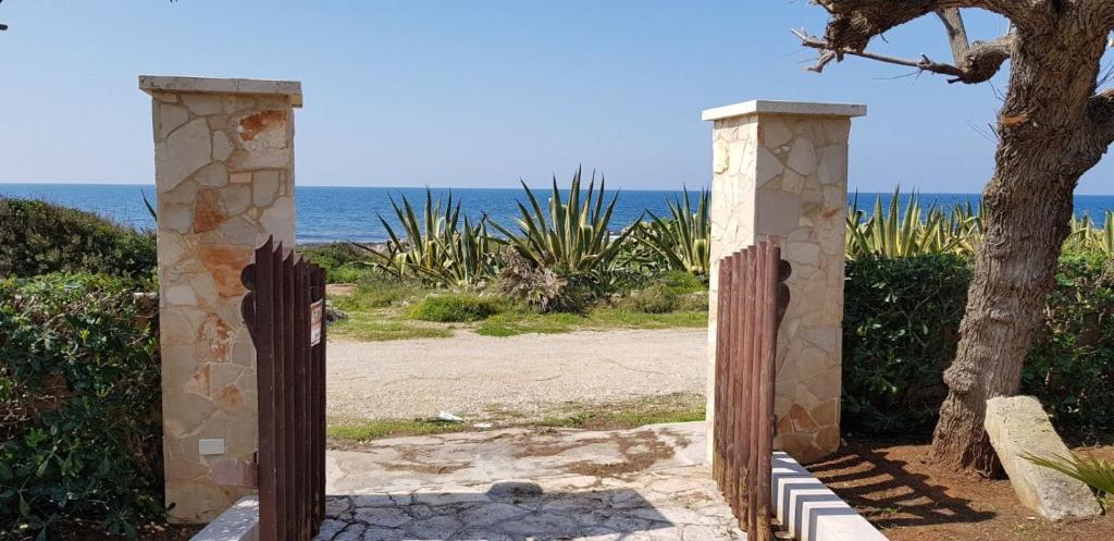 une porte menant à une plage avec l'océan en arrière-plan dans l'établissement Villa Rosaria, à Torre Suda