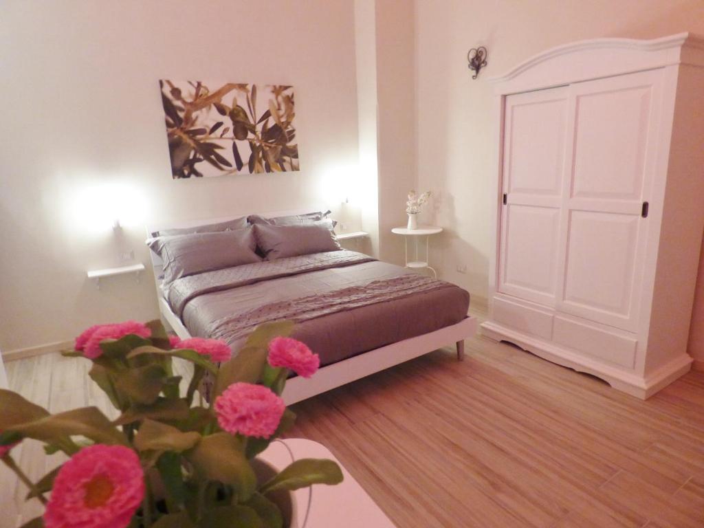 - une chambre avec un lit et une plante ornée de fleurs roses dans l'établissement Da Polly a Piazza Amedeo, à Naples