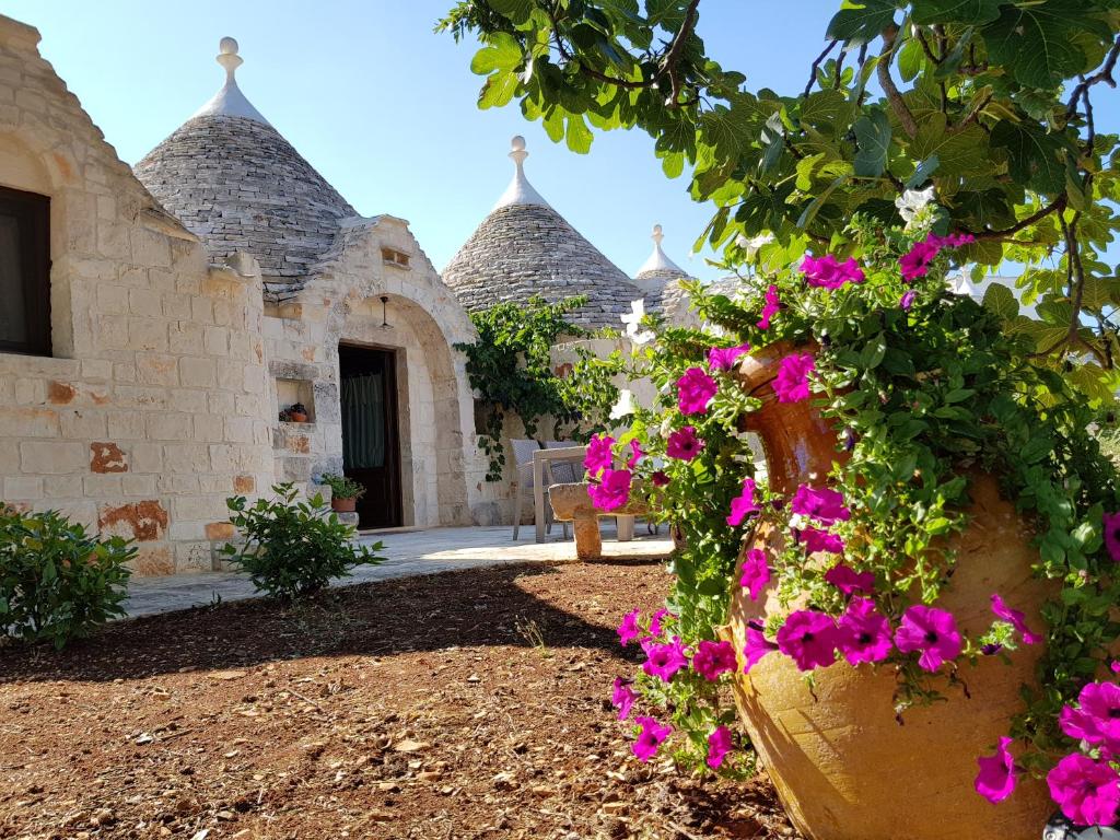 a garden with flowers in front of a building at Almapetra Trulli Resort in Locorotondo
