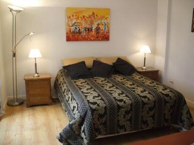 1 dormitorio con 1 cama con 2 lámparas y 1 pintura en Oro Plaza Apartamentos en Buenos Aires