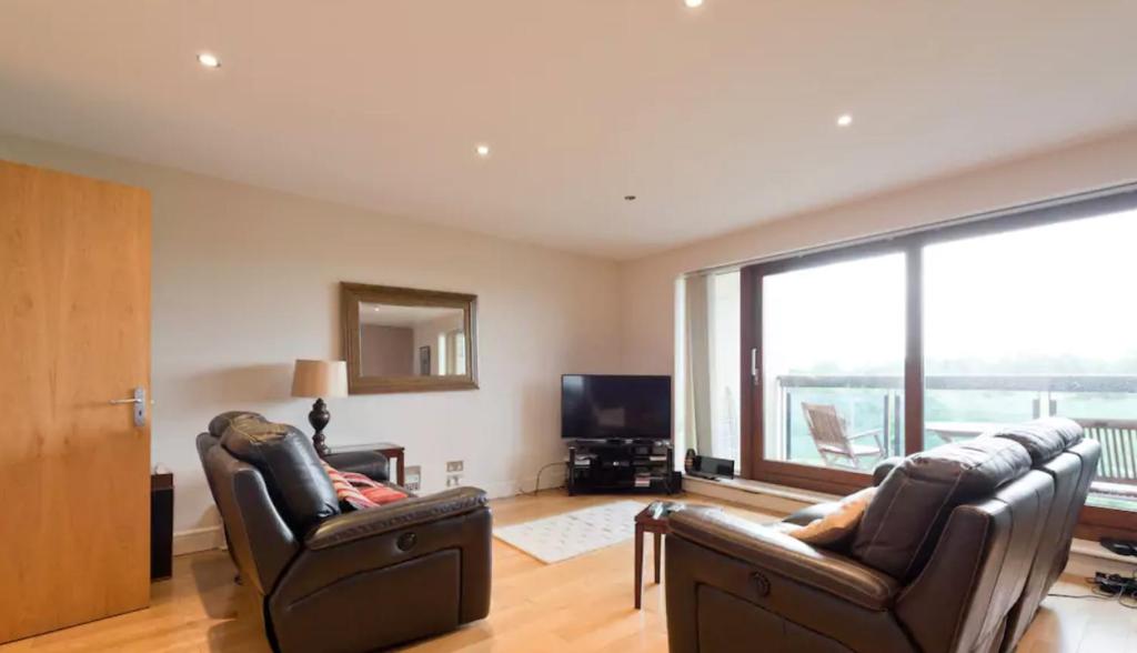 sala de estar con 2 sillas de cuero y TV en Dublin Corporate Apartment, en Lucan