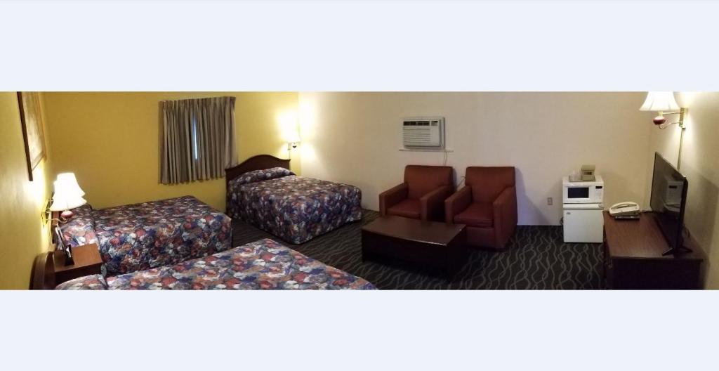 a hotel room with two beds and a chair at Budget Host Inn in Bedford