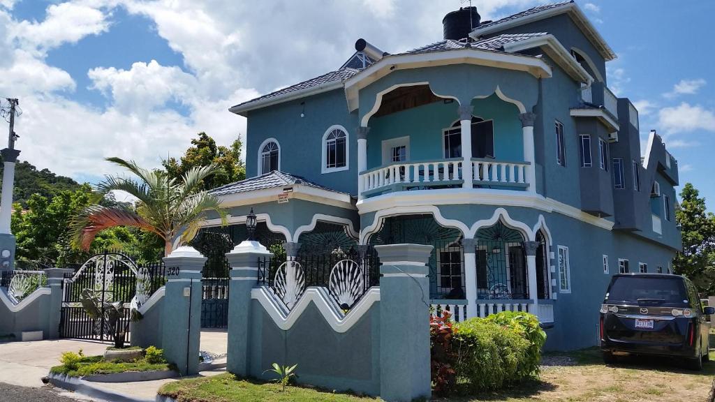 uma casa azul com uma cerca em frente em Bailey's Bed and Breakfast em Runaway Bay