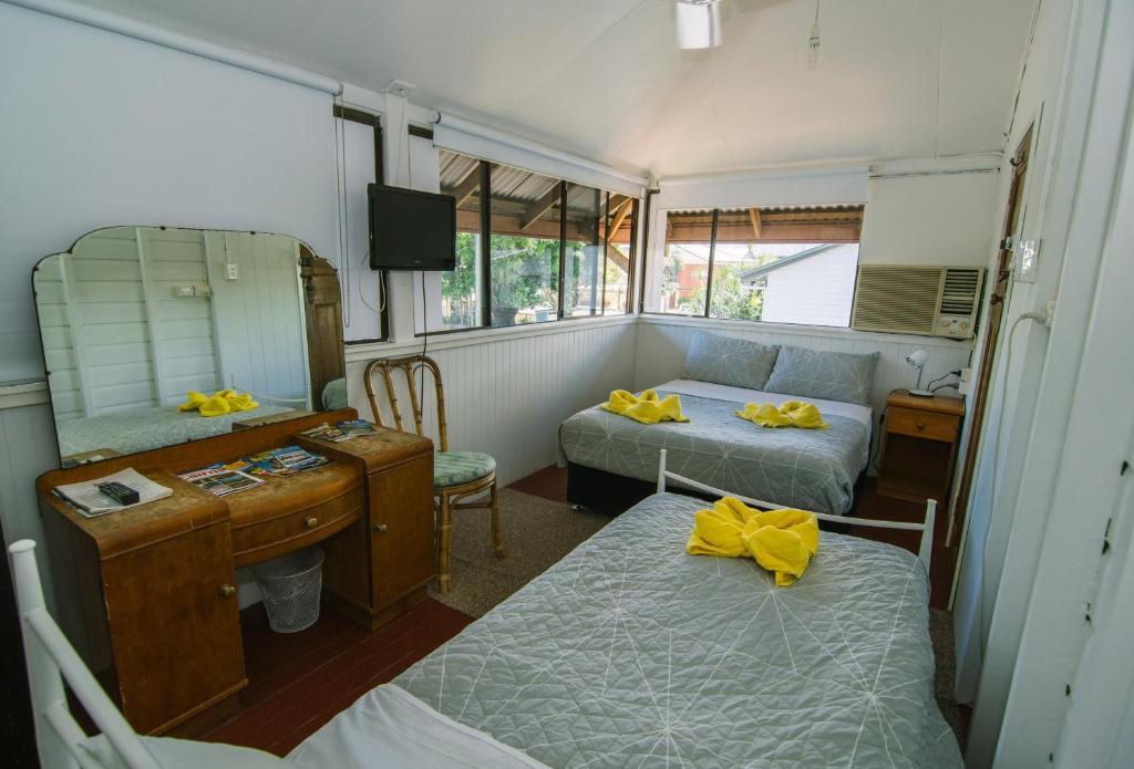 a room with two beds and a desk and a mirror at Ryan's Rest Boutique Accommodation in Cairns