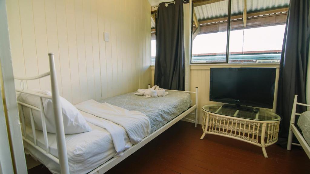 a bedroom with a bed with a television and a window at Ryan's Rest Boutique Accommodation in Cairns