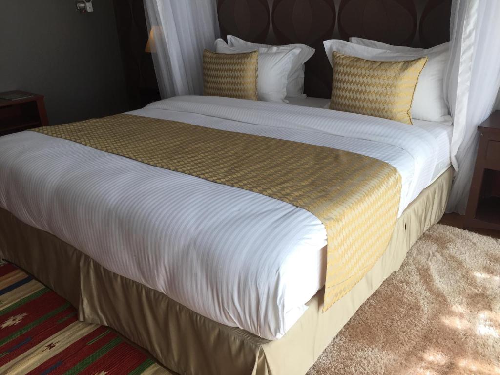a large bed with white sheets and yellow pillows at Salmiya Place 2 in Nairobi