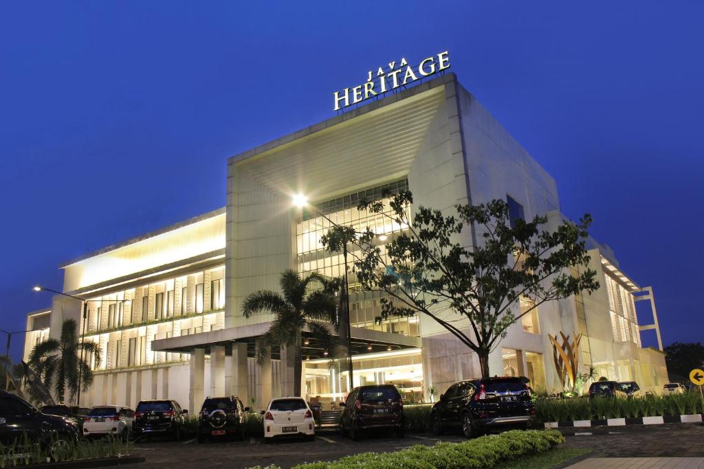 a building with cars parked in front of it at Java Heritage Hotel Purwokerto in Purwokerto