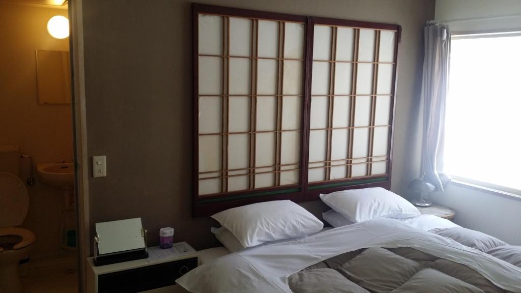 a bed with white sheets and a window in a room at Hakuba Haven Lodge in Hakuba