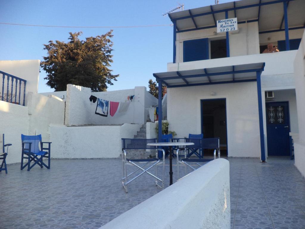a patio with blue chairs and a table in front of a building at Marina's Studios Serifos in Livadi