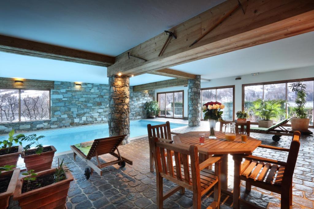 a dining room with a table and chairs and a swimming pool at Hotel Autantic in Bourg-Saint-Maurice