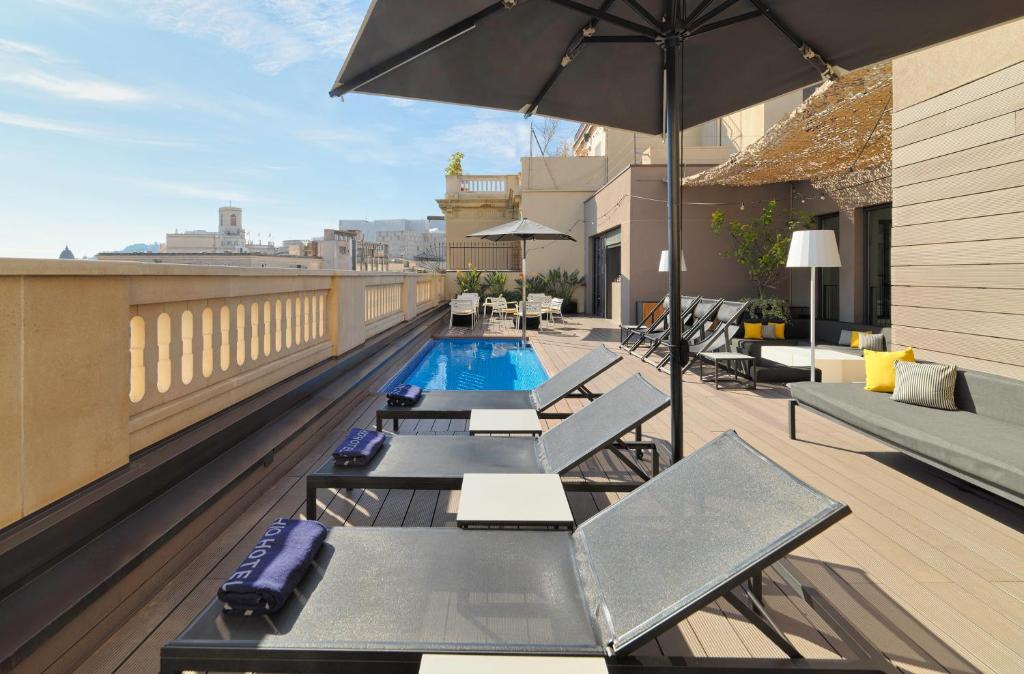 a rooftop patio with a pool and an umbrella at H10 Urquinaona Plaza in Barcelona