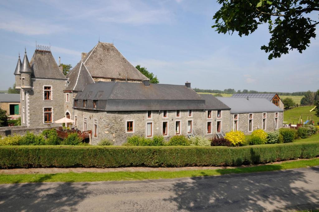 un grand bâtiment en pierre avec un toit dans l'établissement Château Ferme de Laval, à Sainte-Ode