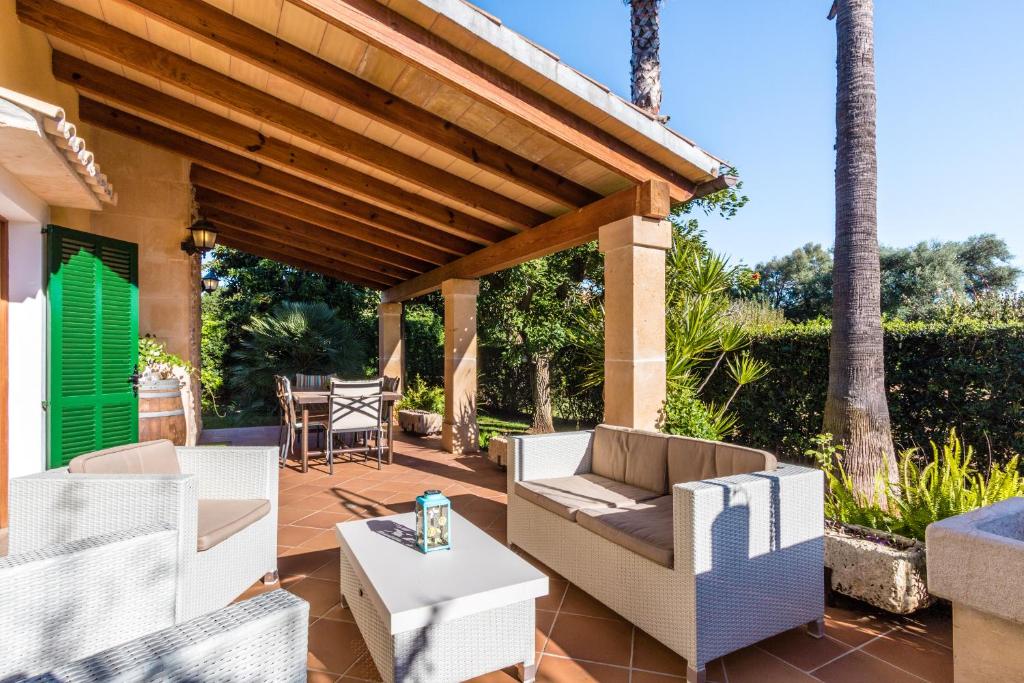 ポリェンサにあるVilla Cuxach By homevillas360の白い家具と木製パーゴラ付きのパティオ