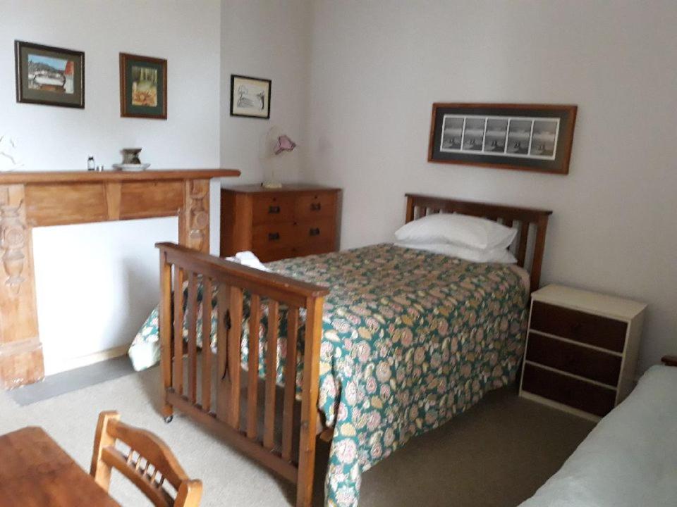 a bedroom with a bed and a dresser and a crib at The Villa in Oamaru