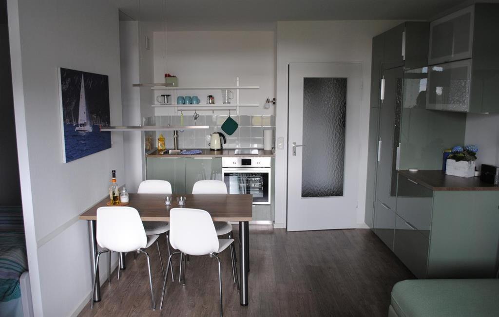 a kitchen with a dining table and white chairs at Ferienwohnung Homeyer in Schilksee