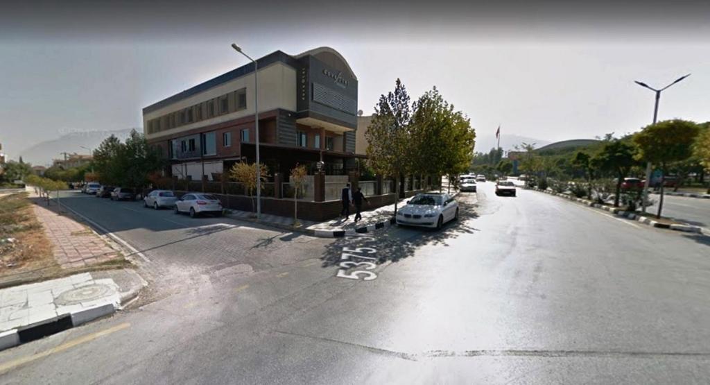 an empty street with cars parked in front of a building at dovsOtel in Manisa