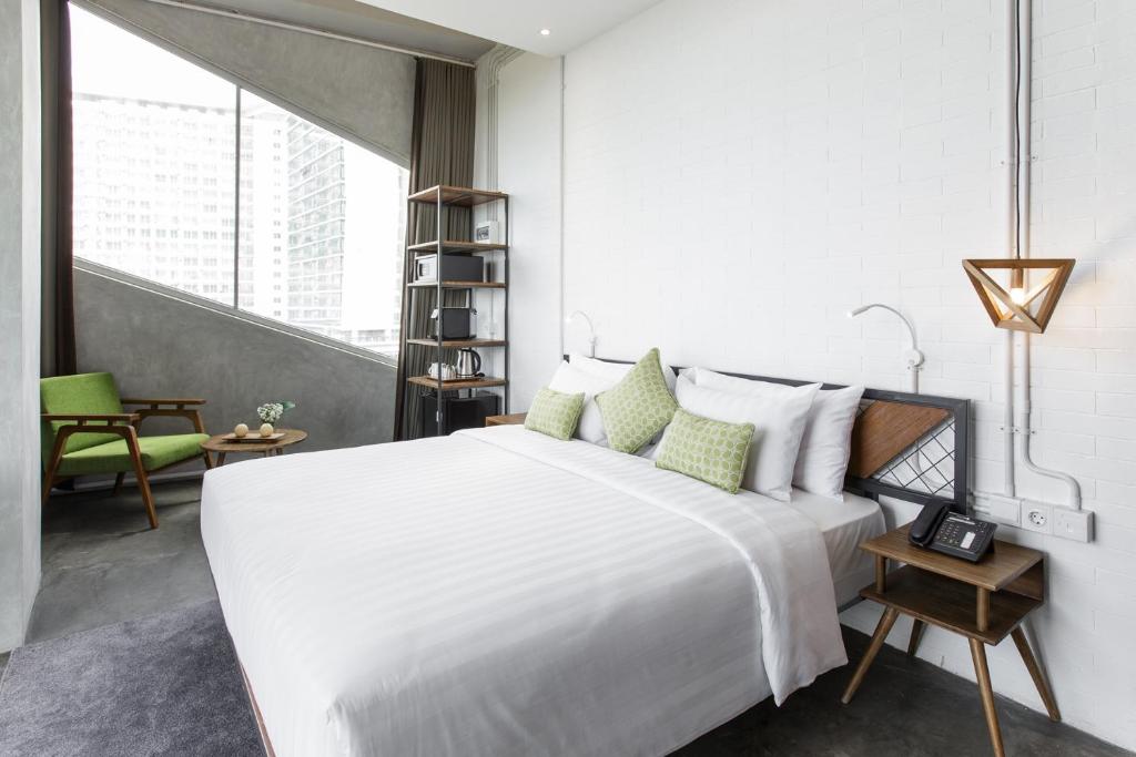 a white bedroom with a large bed and a chair at Janevalla Bandung in Bandung