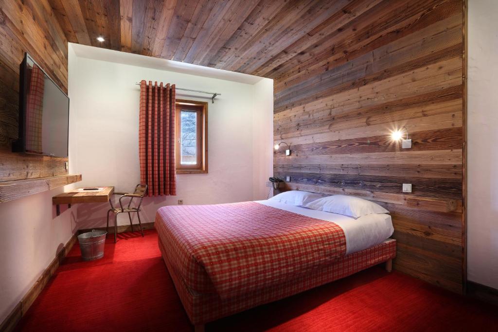 a bedroom with a wooden wall with a bed in it at Hotel Autantic in Bourg-Saint-Maurice