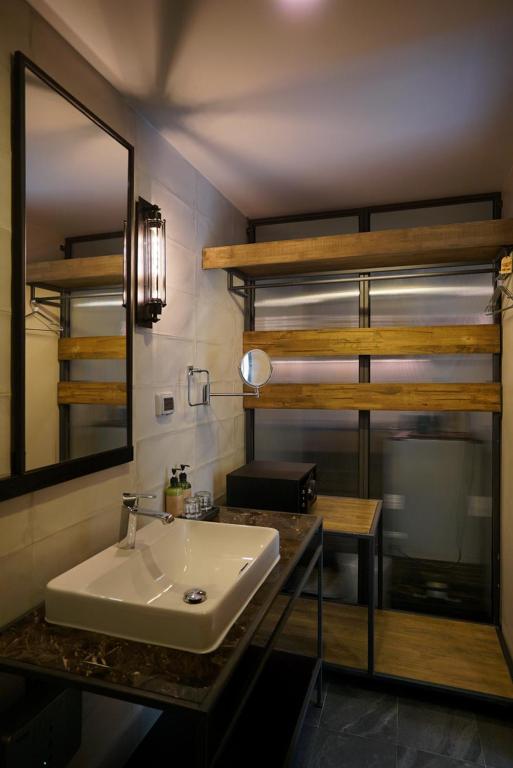 A compact bathroom with a vessel sink, large mirror, glass shower enclosure, and wooden bunk-style shelving.