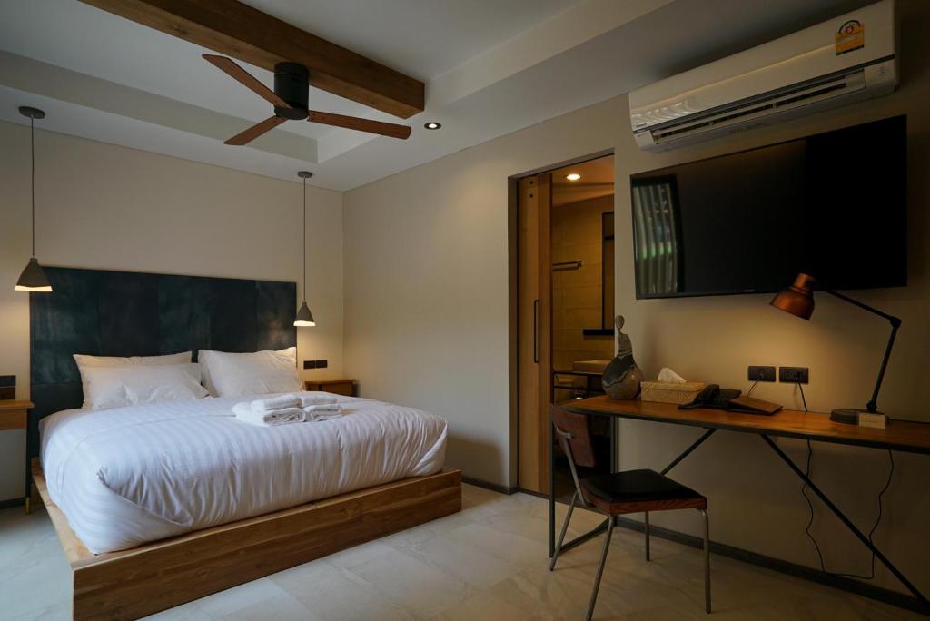 A double bedroom with a wall-mounted TV, compact desk, air conditioner, and ceiling fan.