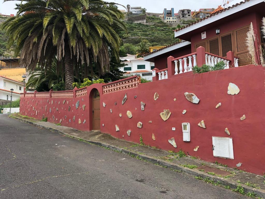 a red wall with rocks on it next to a street at Chalet con vista in Montañeta