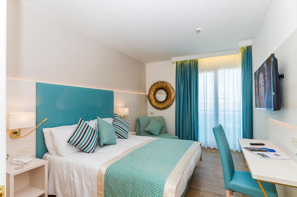 a bedroom with a bed with a blue headboard and a desk at Hotel Montecarlo in Bibione