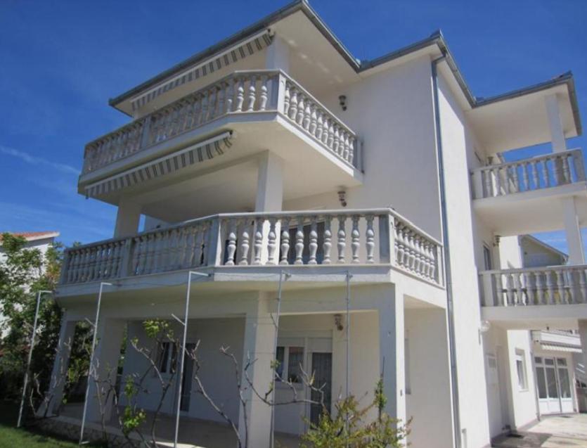 a white building with a balcony on top of it at Apartmani Jureta in Okrug Gornji