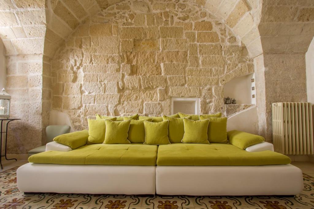 ein Wohnzimmer mit einer grünen Couch vor einer Steinmauer in der Unterkunft Explore the Historic City on foot from an old town house in Lecce