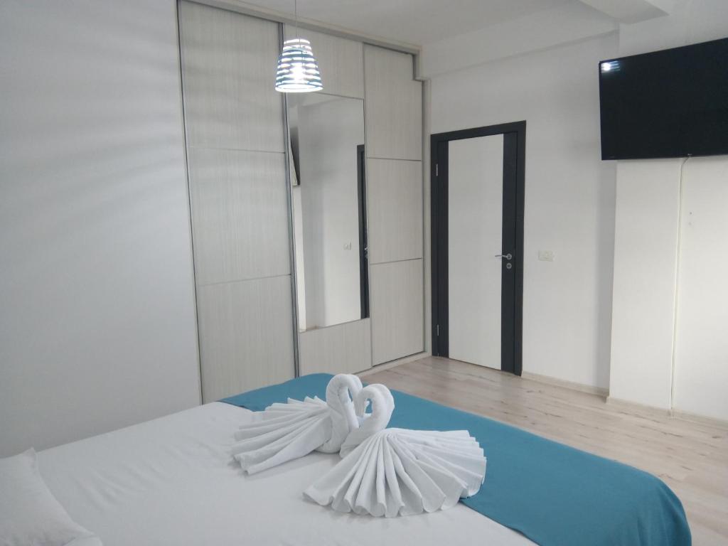 2 cygnes blancs assis sur un lit dans une pièce dans l'établissement Apartament One Kazeboo, à Mamaia Nord – Năvodari