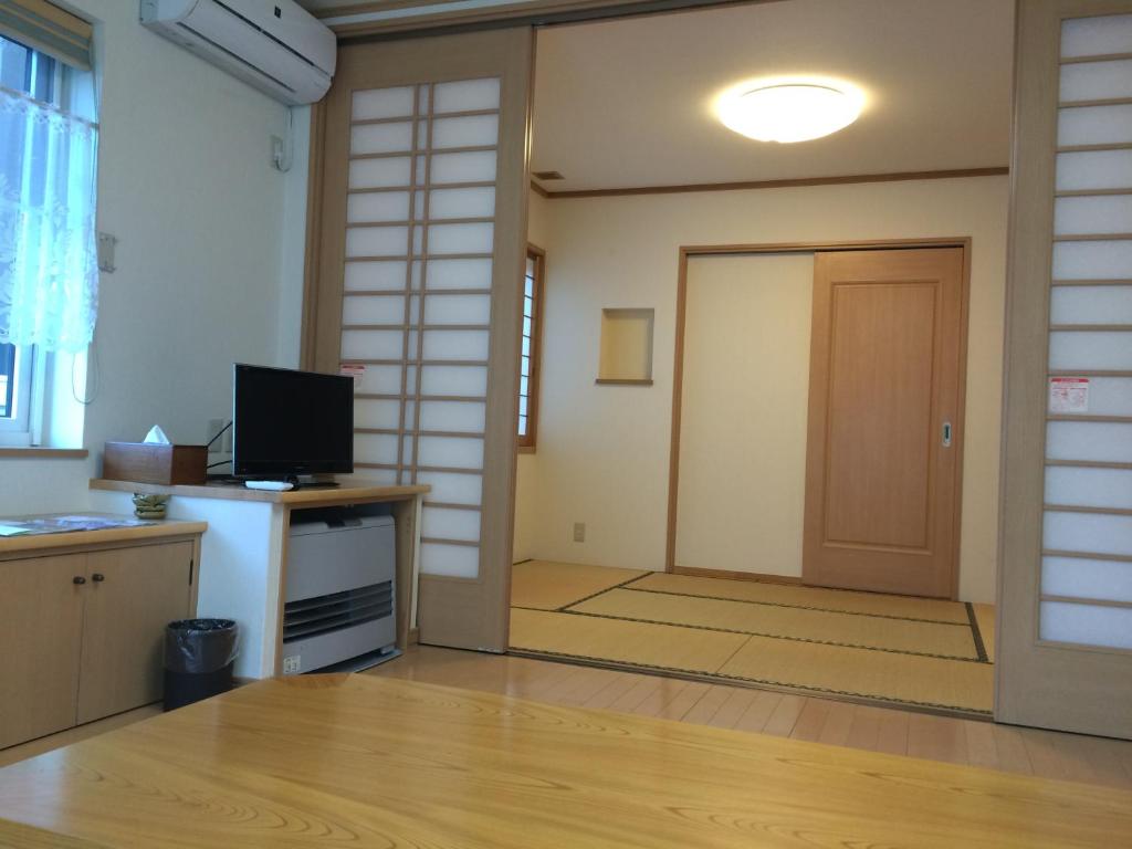 an empty room with a door and a television at Goroji Bekkan in Kusatsu