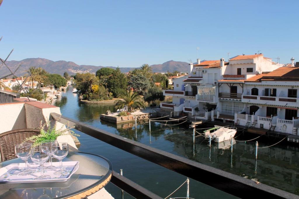 エンプリアブラバにあるEmpurialola - Precioso apartamento vistas a los canales en Empuriabrava- 146のワイングラス付きのバルコニーから川の景色を望めます。