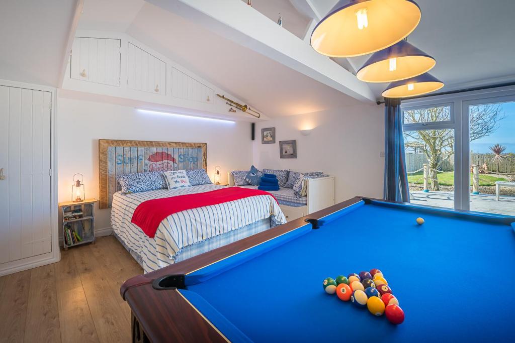 a bedroom with a pool table in front of a bed at Driftwood in Bude