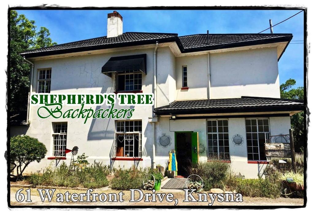 
a house with a sign on the front of it at Shepherd's Tree Backpackers in Knysna
