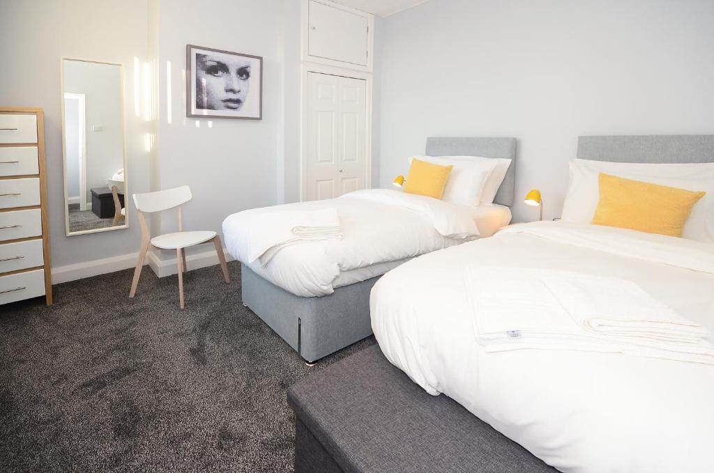 1 dormitorio con 2 camas, silla y espejo en Northwood Park East, en Stoke on Trent