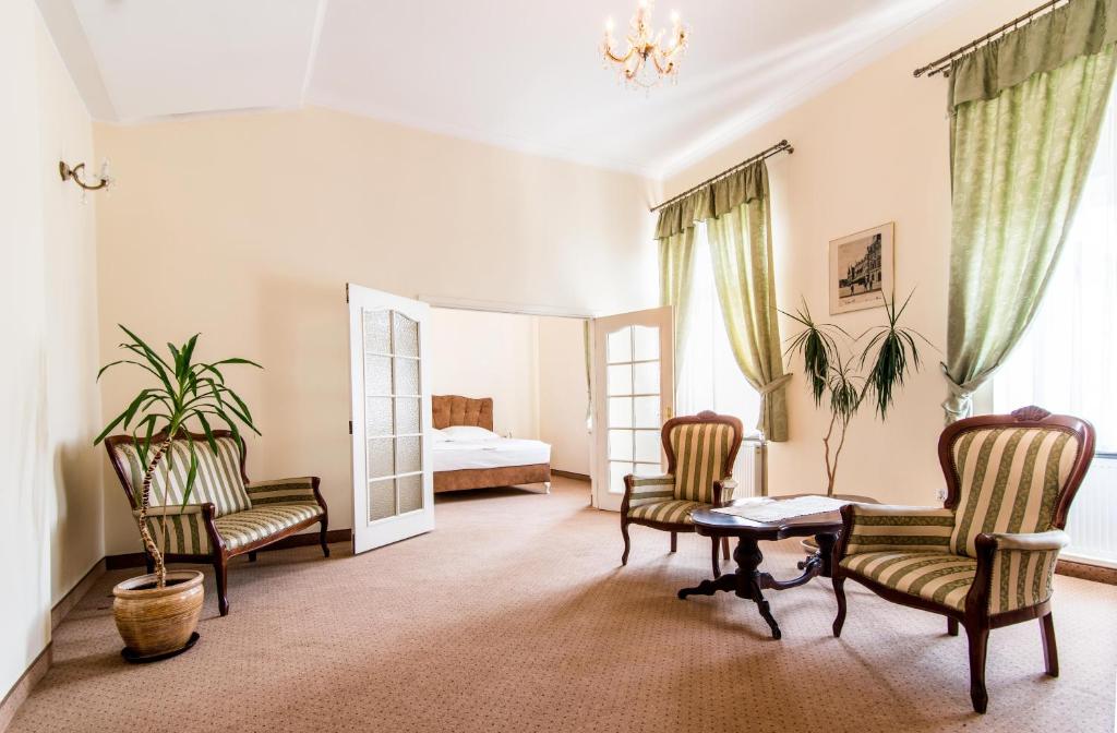 a living room with chairs and a table and a bed at Hotel Piast in Słupsk