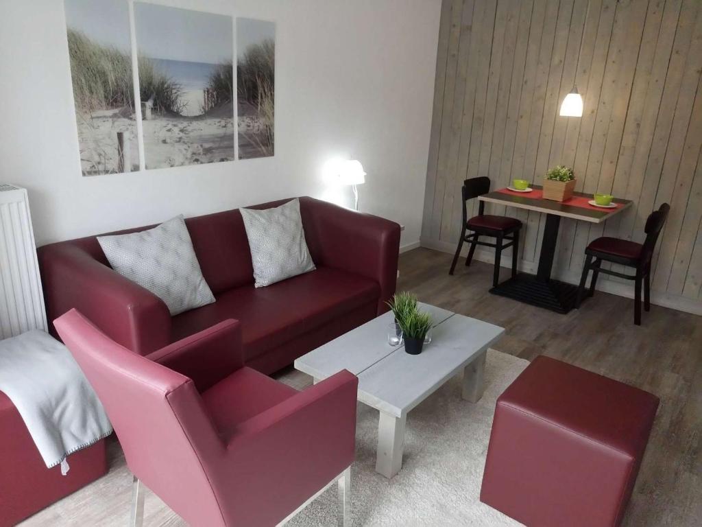 sala de estar con sofá rojo y mesa en dat geele hus Wohnung Nr. 4, en Büsum