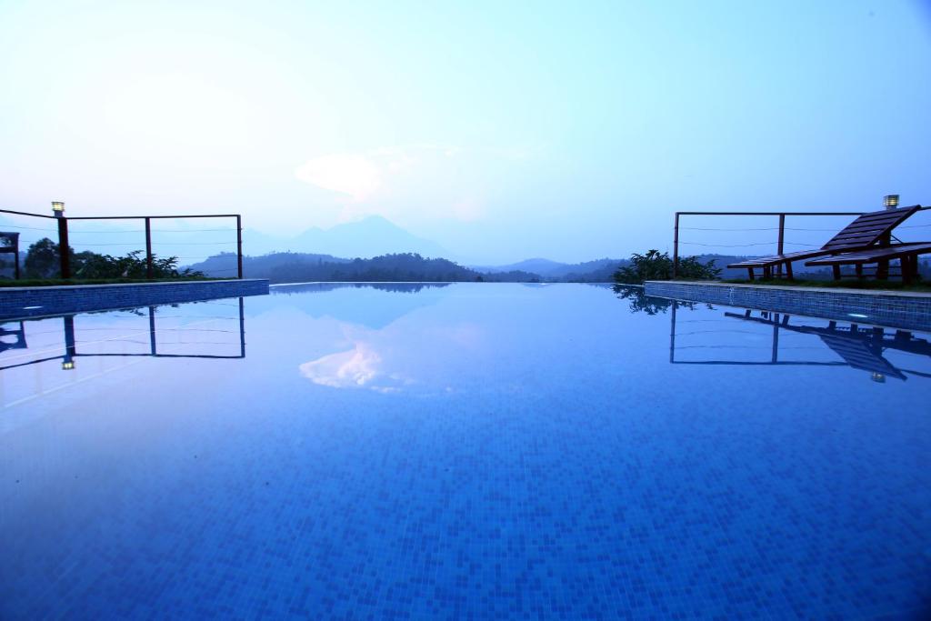 a large pool of blue water with mountains in the background at Petals Resorts Wayanad in Tariyod
