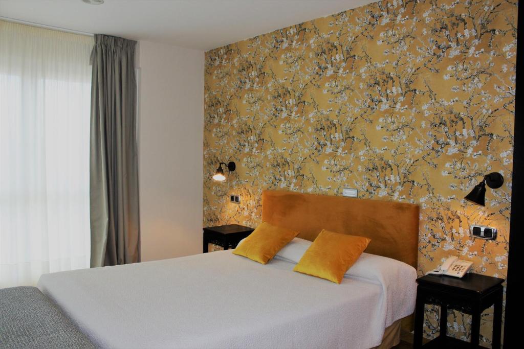 Un dormitorio con una cama con almohadas amarillas. en Hotel Playa de Laxe, en Laxe