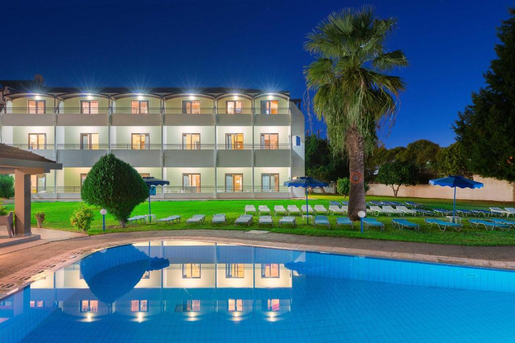 a hotel with a swimming pool in front of a building at Matoula Beach in Ialyssos