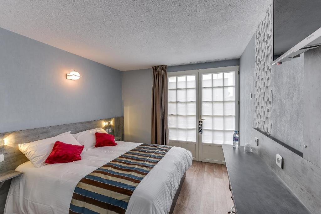 een hotelkamer met een groot bed met rode kussens bij The Originals Access, Hotel Thouars in Thouars