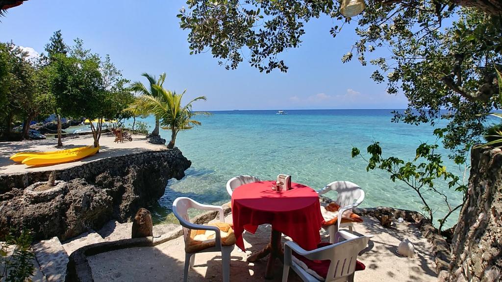 - une table et des chaises sur une plage donnant sur l'océan dans l'établissement Moalboal T Breeze Coastal Resort, à Moalboal