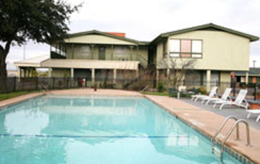 a swimming pool with two chairs and a house at Econo Lodge Inn & Suites in Abilene