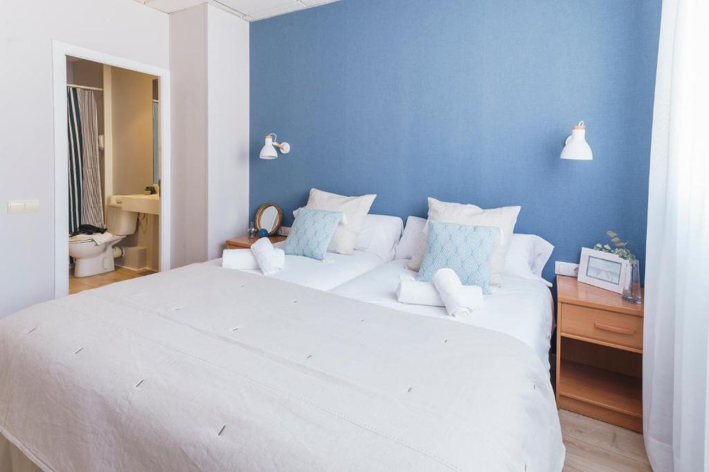 1 dormitorio con 1 cama blanca grande y pared azul en BYPILLOW Mumm, en Vilanova i la Geltrú