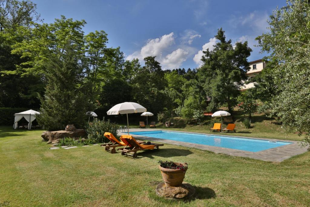 a pool with chairs and umbrellas in a yard at Villa Marina in Terranuova Bracciolini