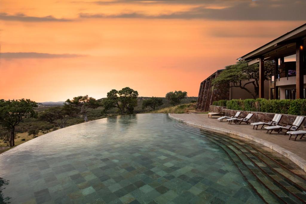 uma grande piscina com cadeiras e um edifício em Meliá Serengeti Lodge Member of Meliá Collection em Banagi
